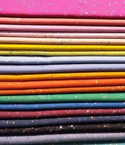 a stack of different colored fabric for quilting